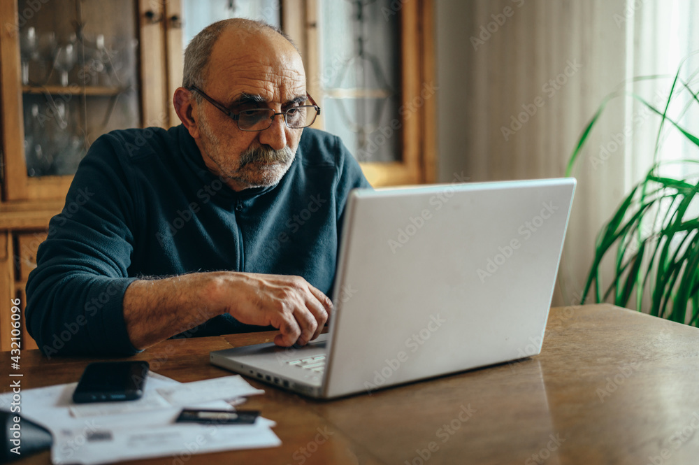 Senior man using a laptop at home Senior man using a laptop at home