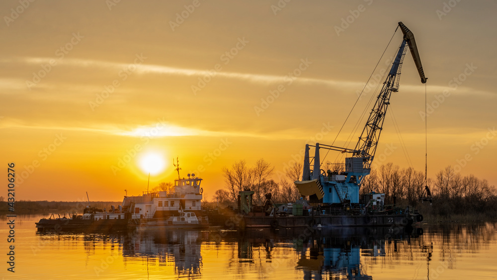 Dredger is working to deepen the fairway on the river. Cleaning and deepening by a dredger on the river. Sunset on the river. Industrial concept.