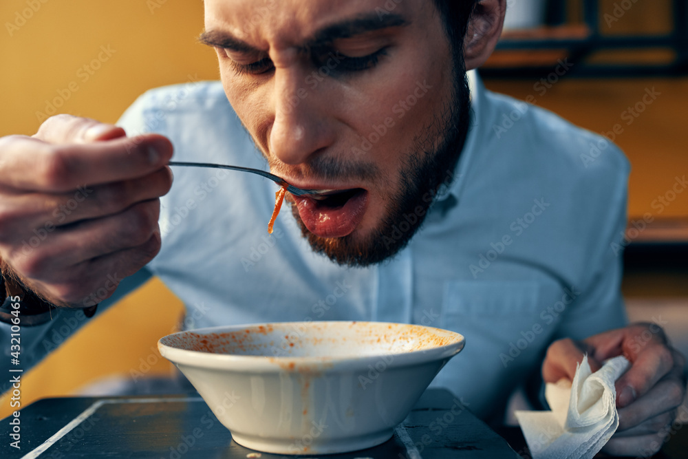 a handsome man with a beard eats borscht in a plate at a table in a cafe and a watch on his hand a handsome man with a beard eats borscht in a plate at a table in a cafe and a watch on his hand