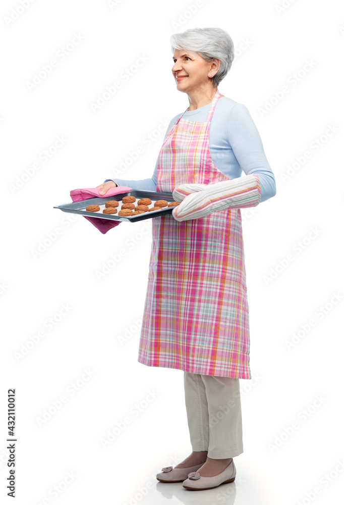 cooking, culinary and old people concept - smiling senior woman in kitchen apron with cookies on baking pan over white background cooking, culinary and old people concept - smiling senior woman in kitchen apron with cookies on baking pan over white background