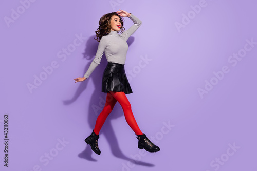 Full size profile side photo of young girl happy smile go walk jump look ahead isolated over violet color background
