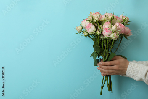 Female hands hold roses on blue background © Atlas