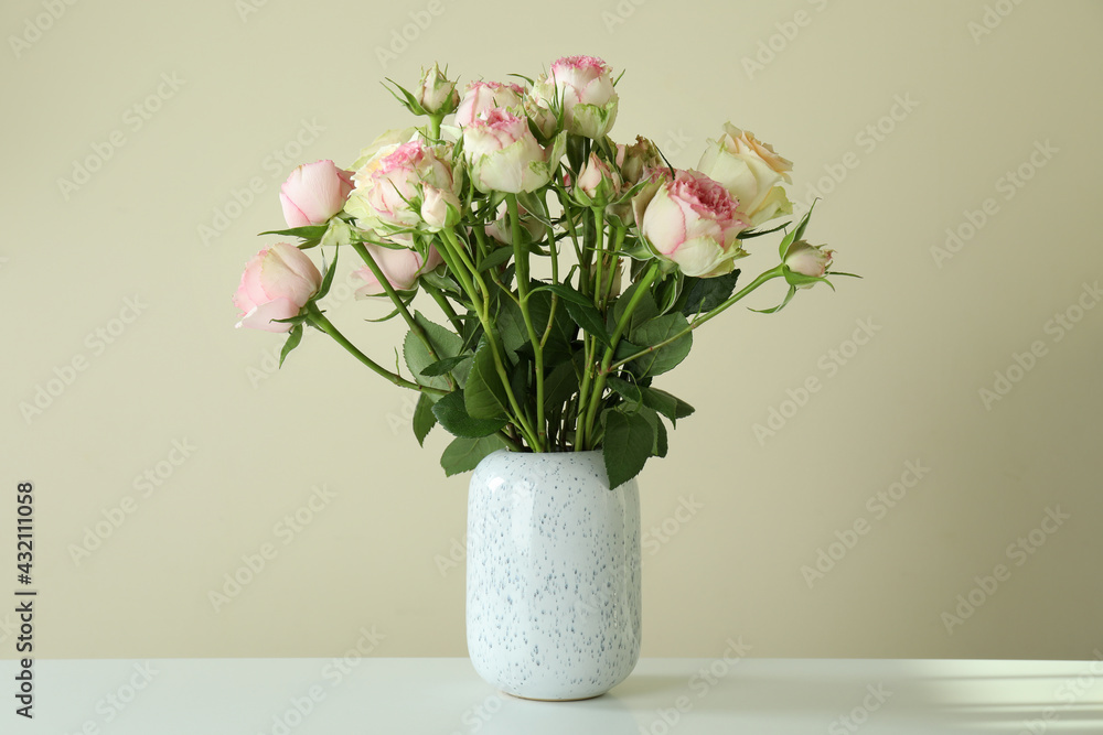 Vase with bouquet of roses on white table