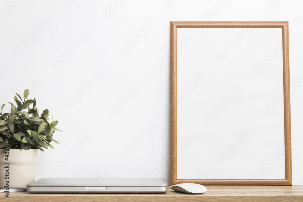 A white photo wooden frame with computer and plant on table. A white photo wooden frame with computer and plant on table.