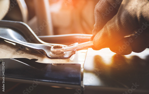 Mechanic hand is unscrewing the metal nut with a combination wrench spanner photo