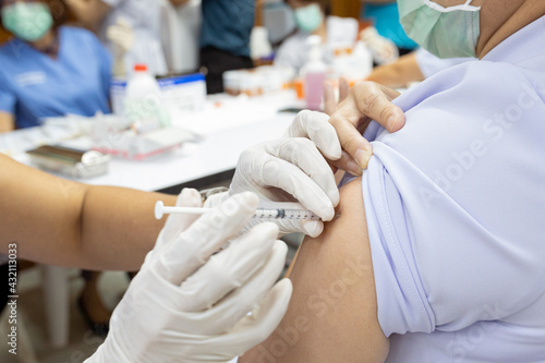 Close up doctor, nurse holding syringe making covid-19 vaccination injection dose in shoulder patient. Corona virus treatment side effect, close up view. Flu Vaccination Injection on Arm.