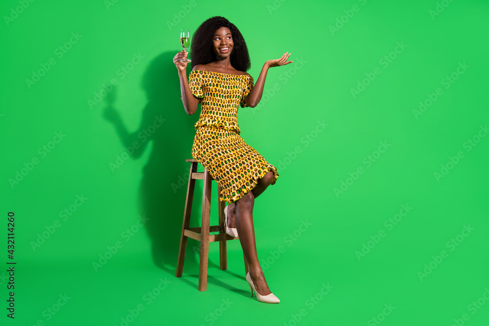 Full size photo of attractive black woman happy positive smile sit bar drink champagne isolated over green color background - obrazy, fototapety, plakaty 