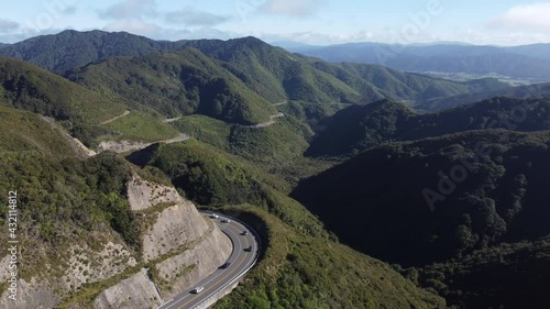 A wide static shot of a winding mountain road with cars driving on it. Rimutaka Hill Road, New Zealand. photo