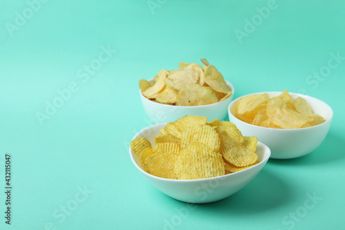 Bowls with potato chips on mint background
