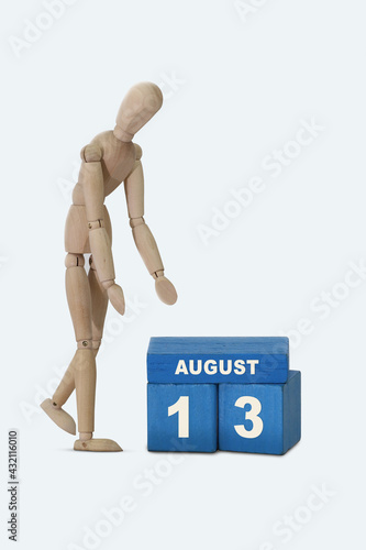 day of the month 13 August calendar . A calendar date on blue cubes and a wooden man standing next to it. White background