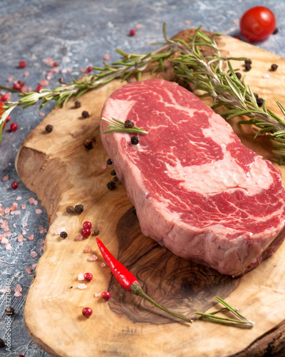 organic raw piece of Prime beef on a wooden Board with spices