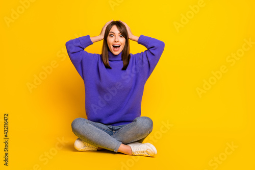 Portrait of attractive cheerful amazed girl sitting in lotus pose great news reaction isolated on bright yellow color background © deagreez