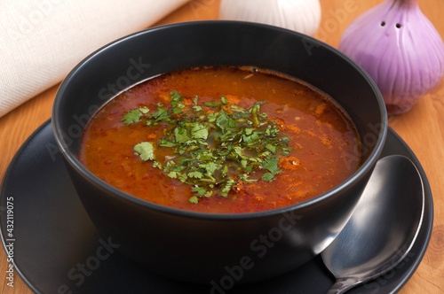 kharcho soup with beef in a dark bowl decorated with greens