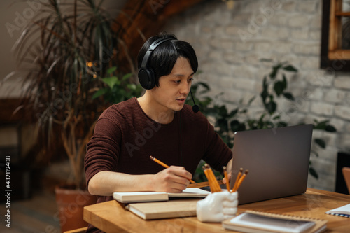 Asian man working at home with earphones on