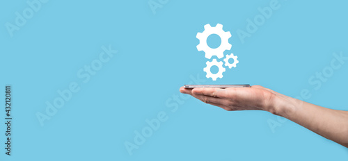 Male hand holding cog gears icon ,mechanism icon on virtual screens on blue background. Automation Software Technology Process System Business concept. Banner