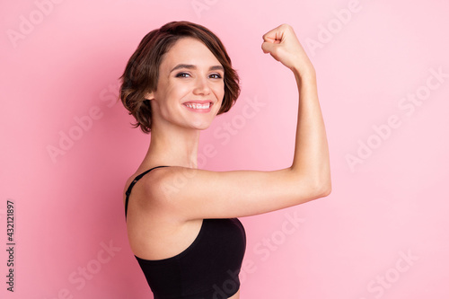 Profile side photo of nice happy young woman show biceps smile good mood isolated on pink color background