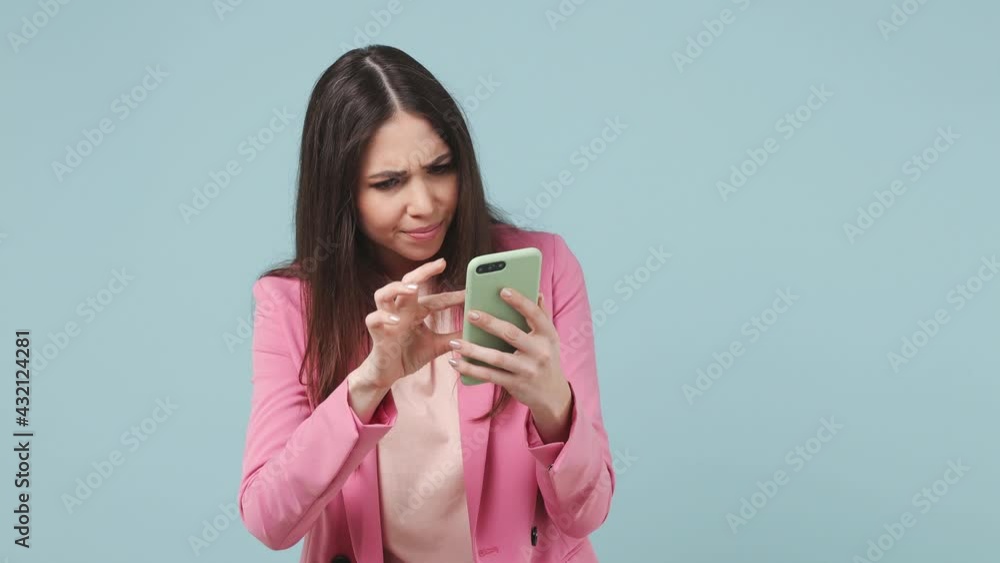 Sad irritated young woman 20s years old wears pink jacket t-shirt using mobile cell phone swear hears fake news unexpected rumor has some problems isolated on pastel blue wall color background studio Sad irritated young woman 20s years old wears pink jacket t-shirt using mobile cell phone swear hears fake news unexpected rumor has some problems isolated on pastel blue wall color background studio