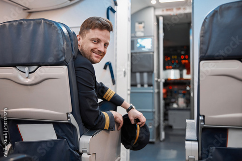 Happy confident caucasian pilot in airplane salon