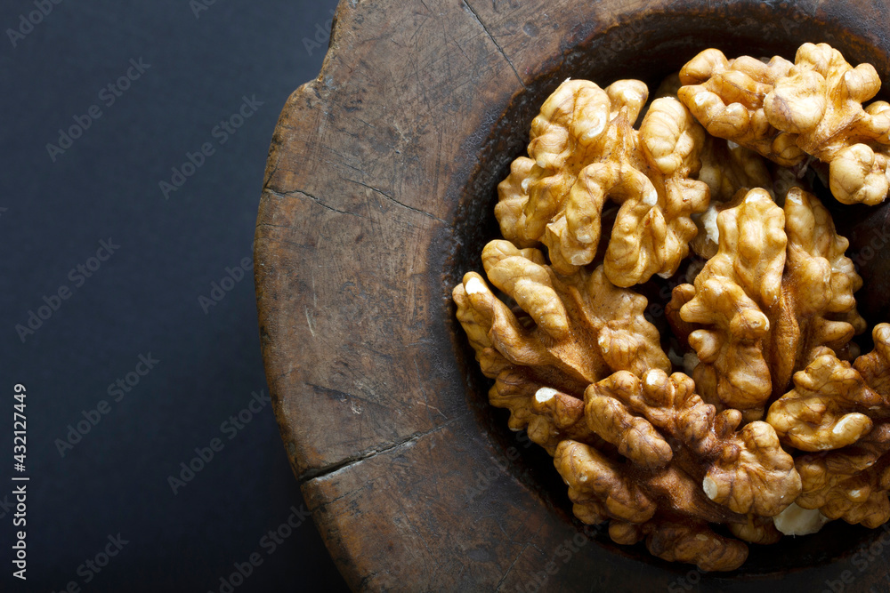 Fototapeta premium Walnuts in antique, wooden mortar.