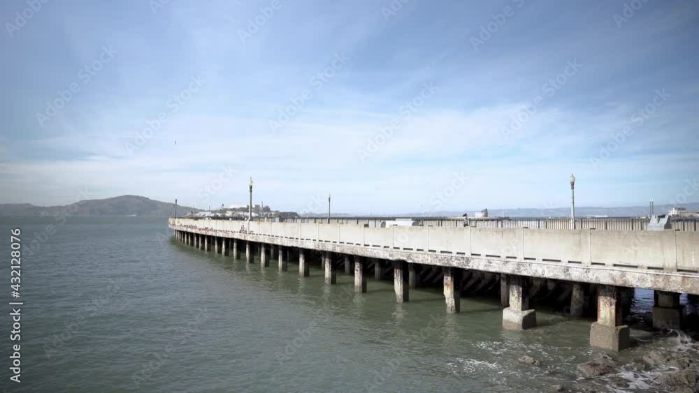 Panorama view of Alcatraz Island and people walking and running on the pier Panorama view of Alcatraz Island and people walking and running on the pier