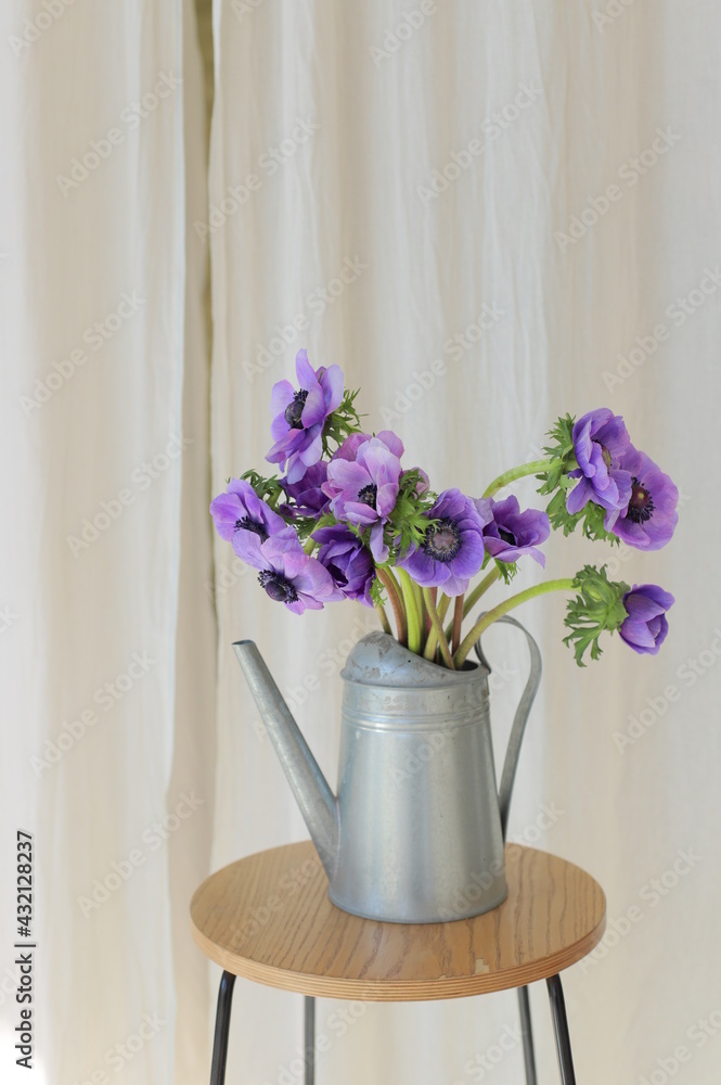 Bouquet of flowers in metal watering can, colored blue anemone.