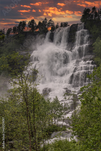 beautiful waterfalls with crystal clear water with mountains in the background at sunset Norway.