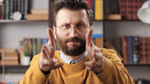 BANG BANG gesture. Frowning man with glasses poses as cowboy and looking at camera pretending that he has pistols in his hands