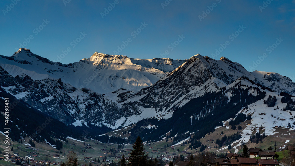 Wildstrubel und Steghorn überragen die Engstligenalp in Adelboden. Schnee von gestern liegt im Frühling auf den Wäldern, Wiesen und Dächern. snowy mountains in Switzerland