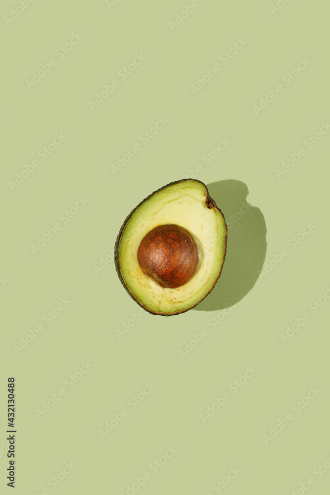A top view on a half of an avocado on a pastel green surface