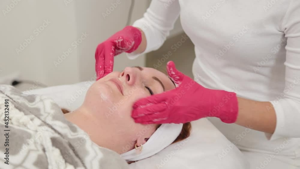 Woman beautician massages the face of a client. Woman beautician massages the face of a client.