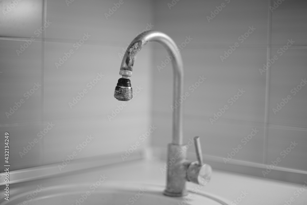 Old chrome faucet in the kitchen covered with lime scale. Black and white photo. Old chrome faucet in the kitchen covered with lime scale. Black and white photo.