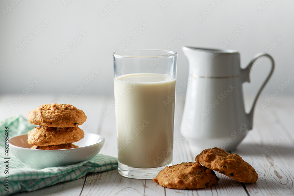 A fresh glass of milk with chocolate chip cookies on white wooden background. Healthy eating. Selective focus. A fresh glass of milk with chocolate chip cookies on white wooden background. Healthy eating. Selective focus.