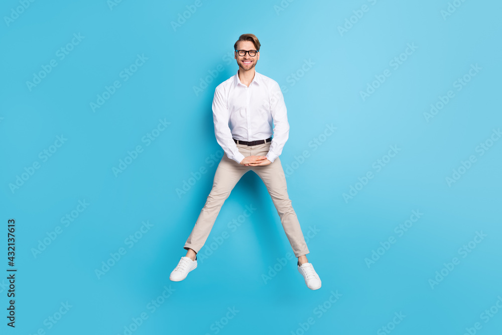 Full length body size view of attractive funky cheerful man jumping having fun posing isolated over bright blue color background Full length body size view of attractive funky cheerful man jumping having fun posing isolated over bright blue color background