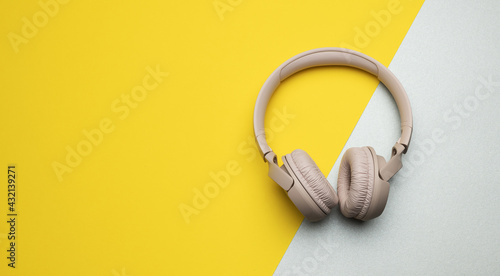 pink wireless headphones on a gray-yellow background, top view. Modern gadget