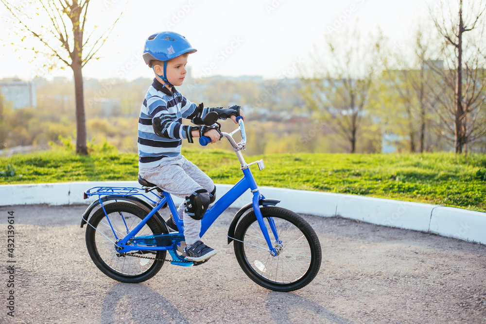 Obraz premium A child in a helmet and protection in a bike ride on nature in the spring
