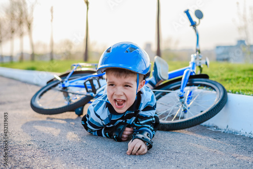 Fotografija A small child fell from a bicycle onto the road, crying and screaming in pain
