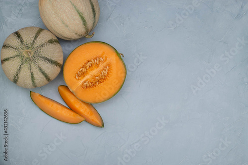 Melons and slices on light blue stone background. Summer concept photo.