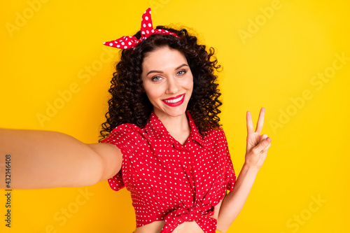 Photo of cute optimistic brunette hair lady do selfie show v-sign wear red top band isolated on yellow color background