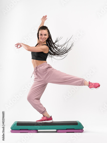 Fotografie An attractive, smiling woman with Afro-pigtails is engaged in step aerobics
