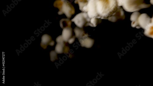 Sweet popcorn drops on isolated black background in slowmotion.