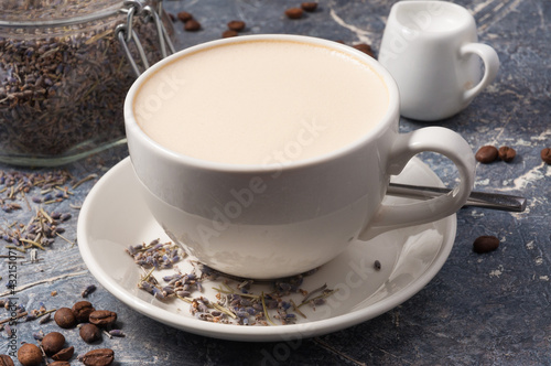 a Cup of coffee with milk and lavender on a gray background with coffee beans