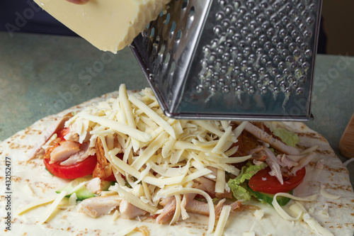 A girl is rubbing cheese on ingredients in a close-up