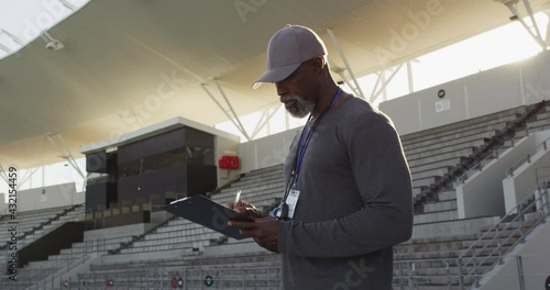 Smiling african american male coach making notes on sunny day photo