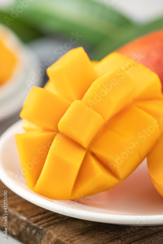 Diced fresh mango fruit on a white plate with leaves.