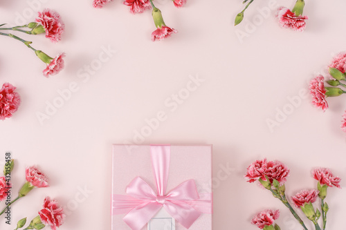 Mother's day background. Top view of gift with carnation bouquet on pink table background