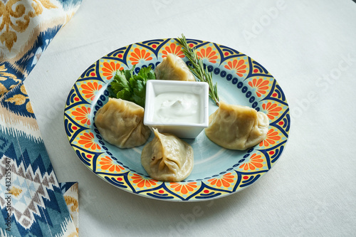 Close up view on traditional Turkish Manti Manlama stuffed with minced meat with Yogurt and Tomato sauce in plate on white background. Manty photo