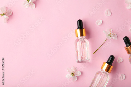 Beauty cosmetic skincare oil in bottle. Products with flower on pink background. Top view