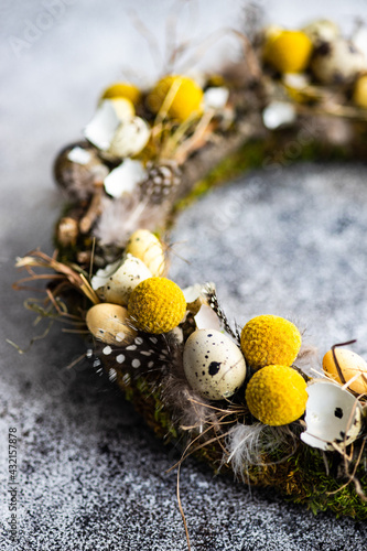 Close-Up of an Easter wreath decorated with quail eggs and feathers on a table photo