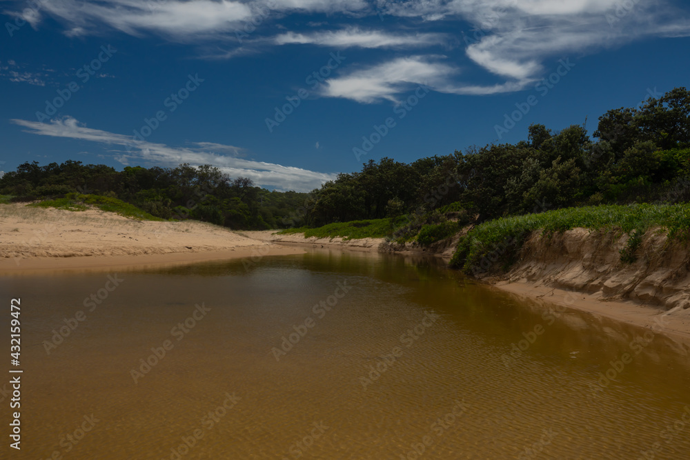 A small, natural creek with clear, unpolluted water coming from the undeveloped national park bushland at the rear of this beach on the east coast of Australia.