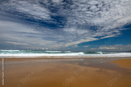 Landscape sandy beach with a beautiful series of cloud patterns and types of reflections on the beach and surf waves on the east coast of Australia. © IKT224
